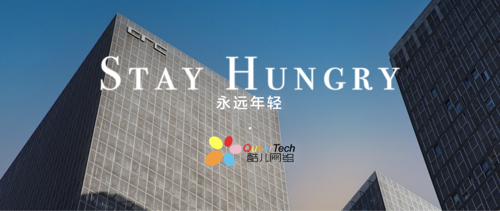 Stay Hungry: QueerTech’s reminder to stay curious, set against a blue sky and city buildings.